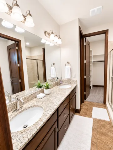 Dual vanity with integrated sinks, granite countertop, and dark wood cabinetry