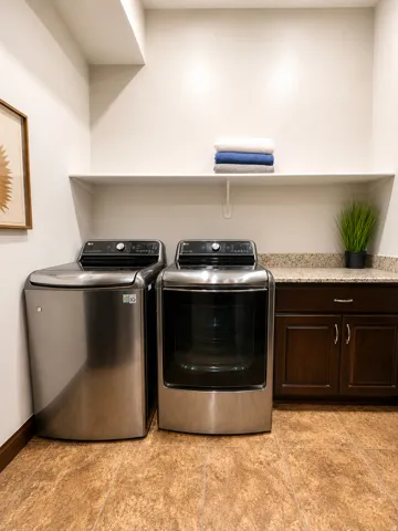 Spacious laundry area featuring durable flooring, built-in cabinetry, and countertop space with an integrated shelf