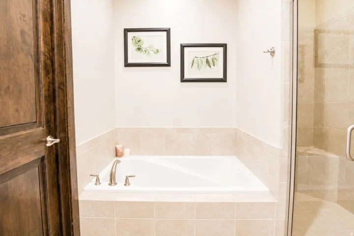Built-in soaking tub with brushed nickel fixtures, surrounded by neutral-toned tile
