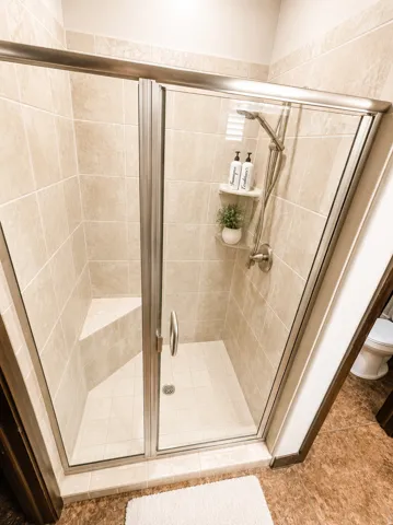Glass-enclosed shower with tiled walls and a built-in bench