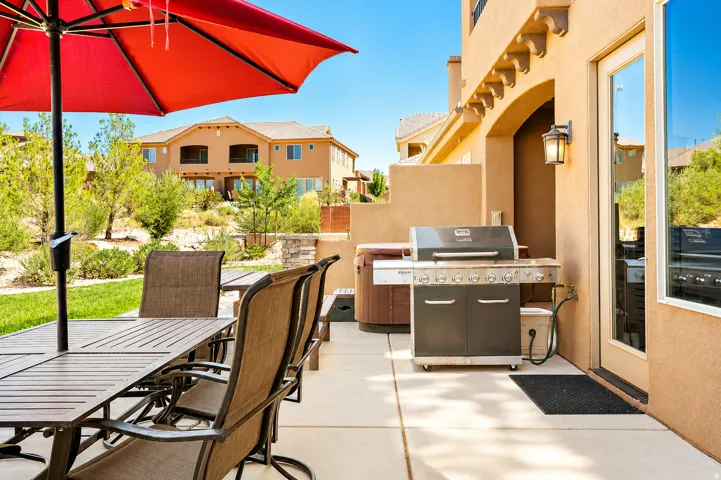 Outdoor patio featuring a built-in grill station, privacy wall, and exterior lighting