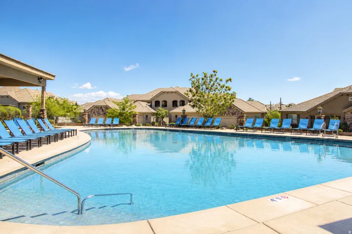 Sparkling swimming pool with concrete decking, covered poolside lounge area, and surrounding multi-story residential buildings