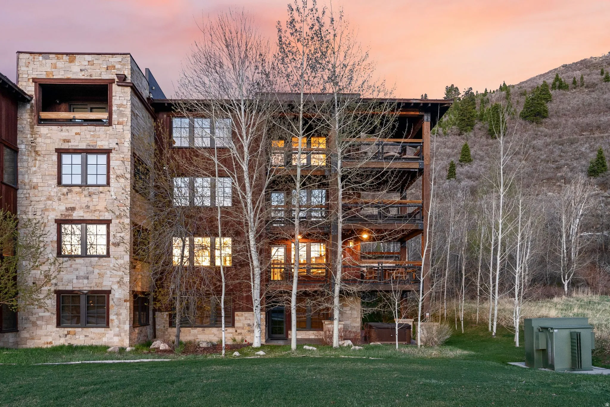 View of front of house featuring a front lawn, stone siding, and a balcony