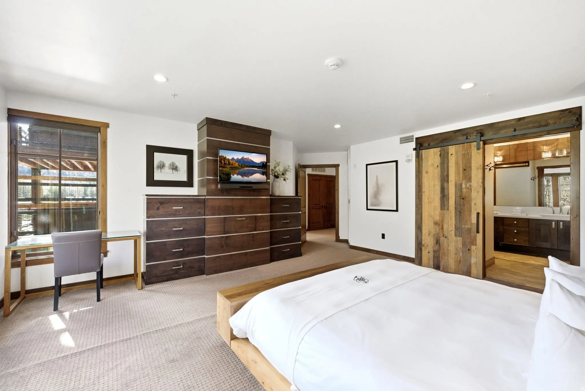 Carpeted bedroom featuring a barn door, connected bathroom, recessed lighting, and an office area