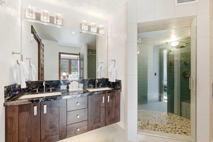 Full bathroom featuring double vanity, a shower stall, and light tile patterned floors