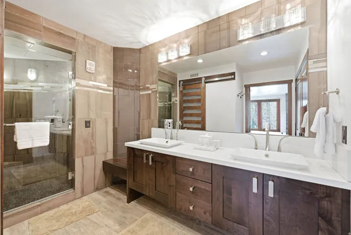 Bathroom with double vanity, a stall shower, and light wood finished floors