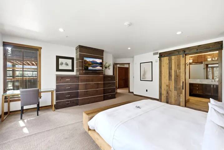 Carpeted bedroom featuring a barn door, connected bathroom, recessed lighting, and an office area