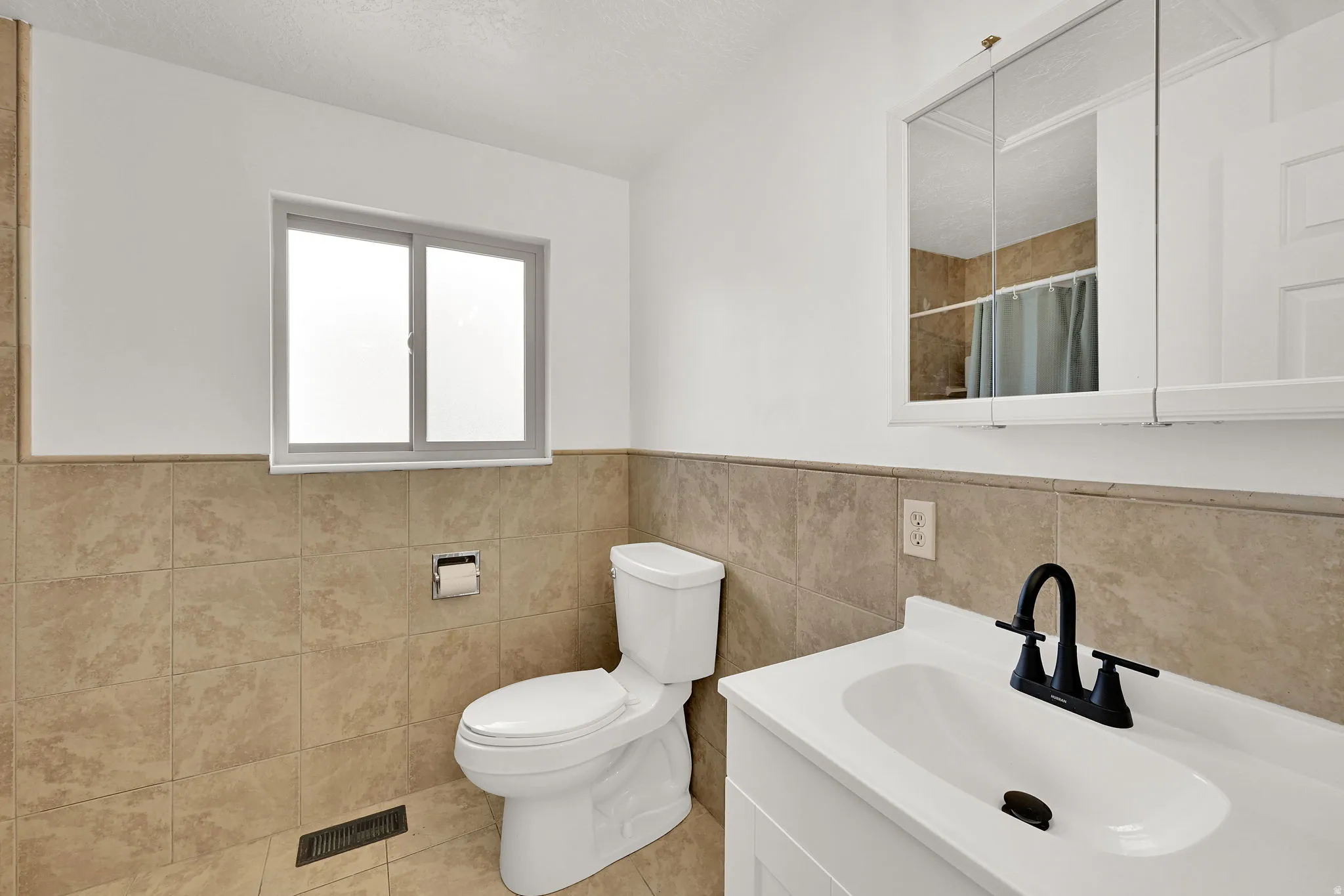 Bathroom with vanity, wainscoting, tile walls, curtained shower, and light tile patterned floors