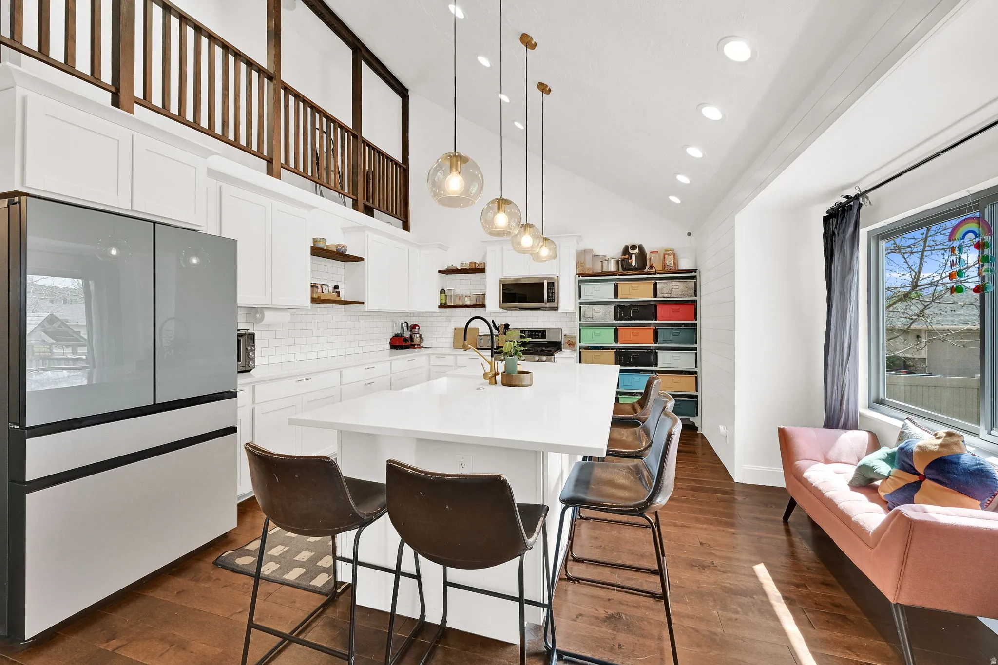 Kitchen with stainless steel appliances, open shelves, white cabinetry, a kitchen island with sink, and vaulted ceiling