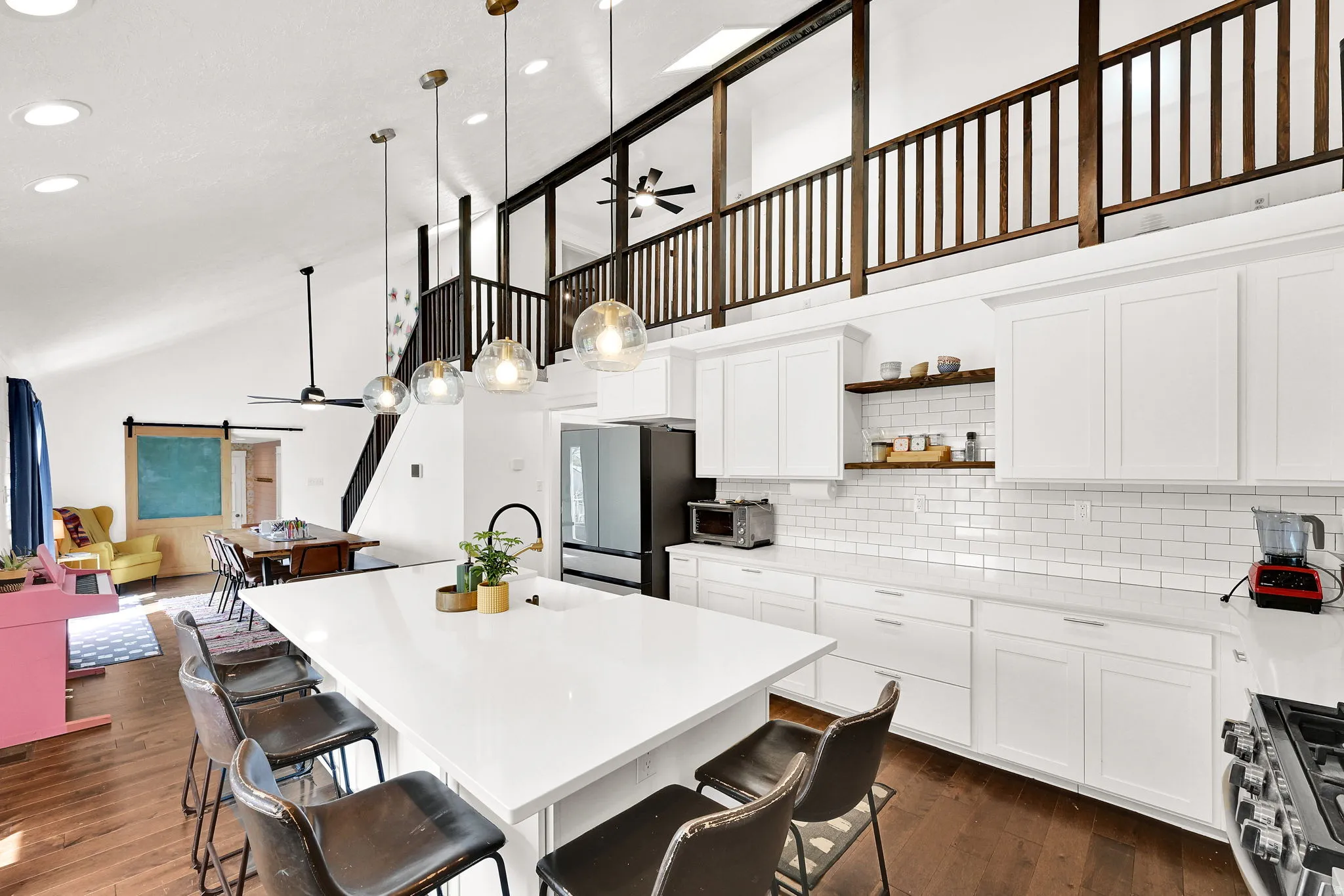 Kitchen with a ceiling fan, white cabinetry, a breakfast bar area, and lofted ceiling