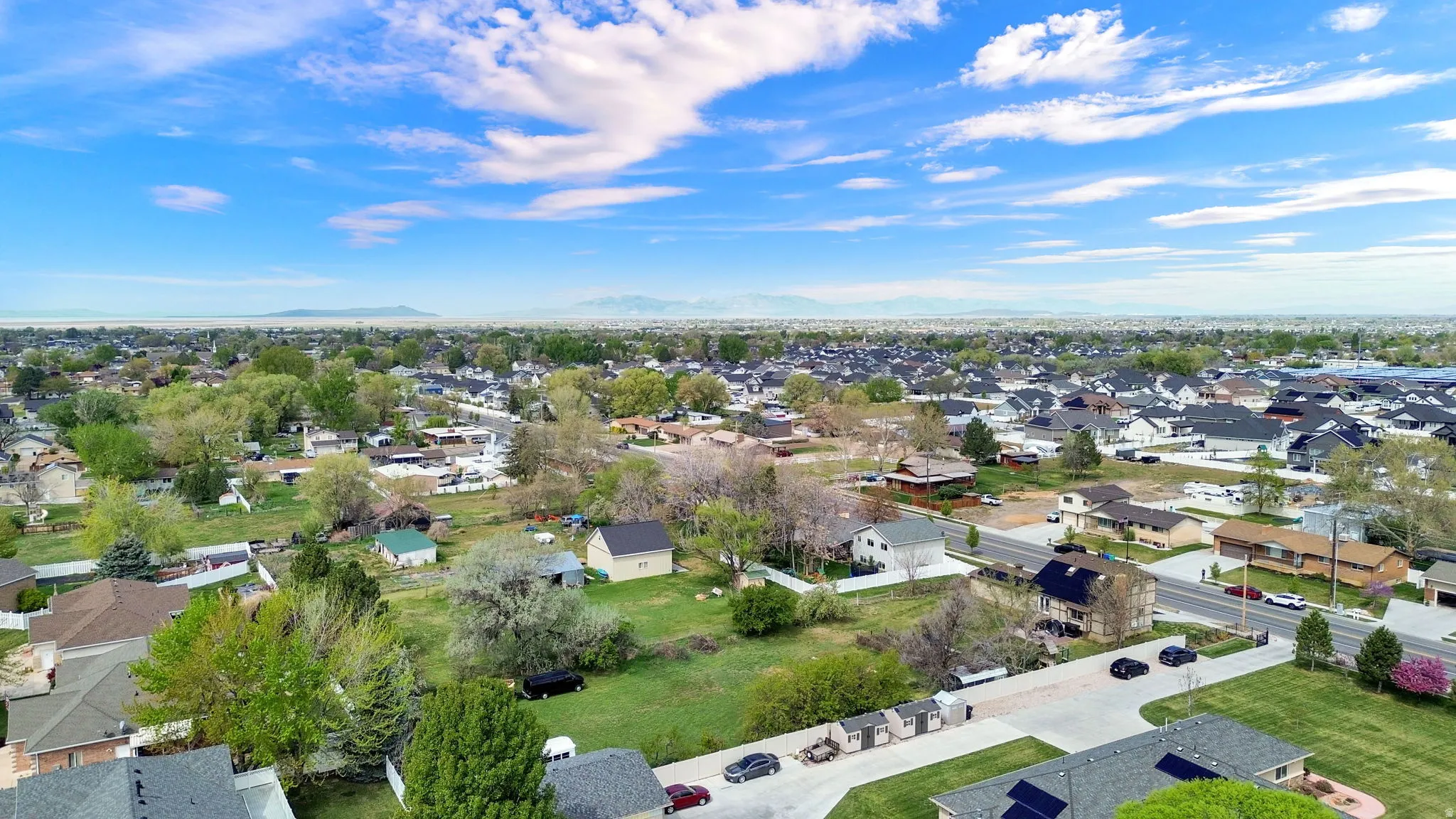 Aerial view of property and surrounding area featuring nearby suburban area and a mountain backdrop