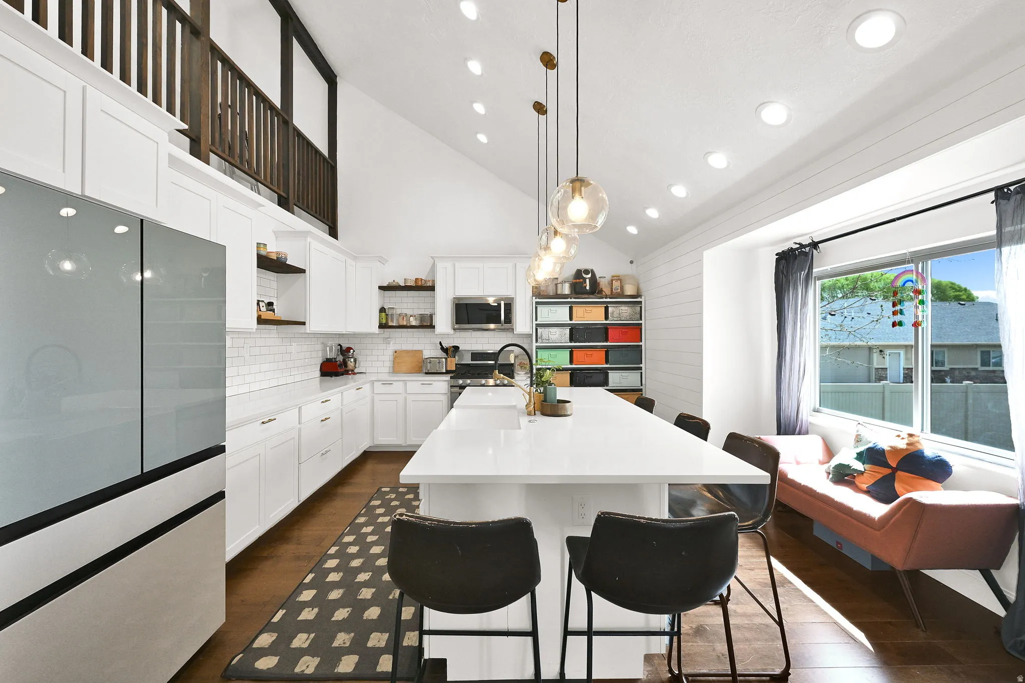 Kitchen with stainless steel appliances, vaulted ceiling, white cabinetry, a kitchen bar, and dark wood-type flooring