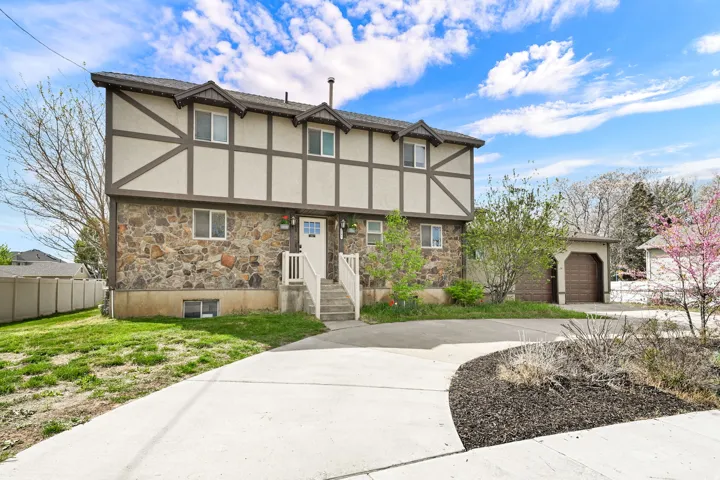 Tudor-style house featuring stone siding, stucco siding, and driveway