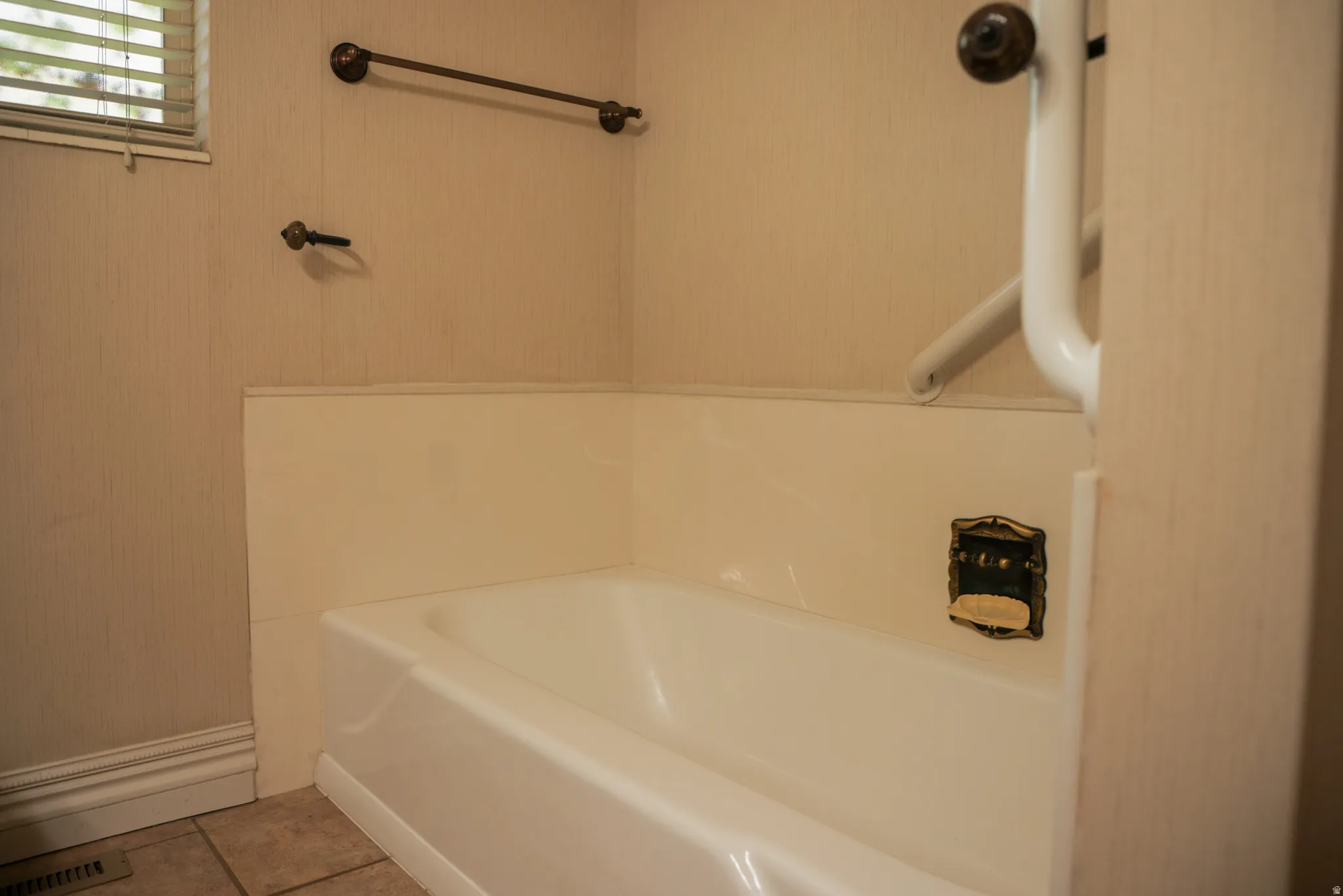 Full bath featuring a bath and light tile patterned flooring