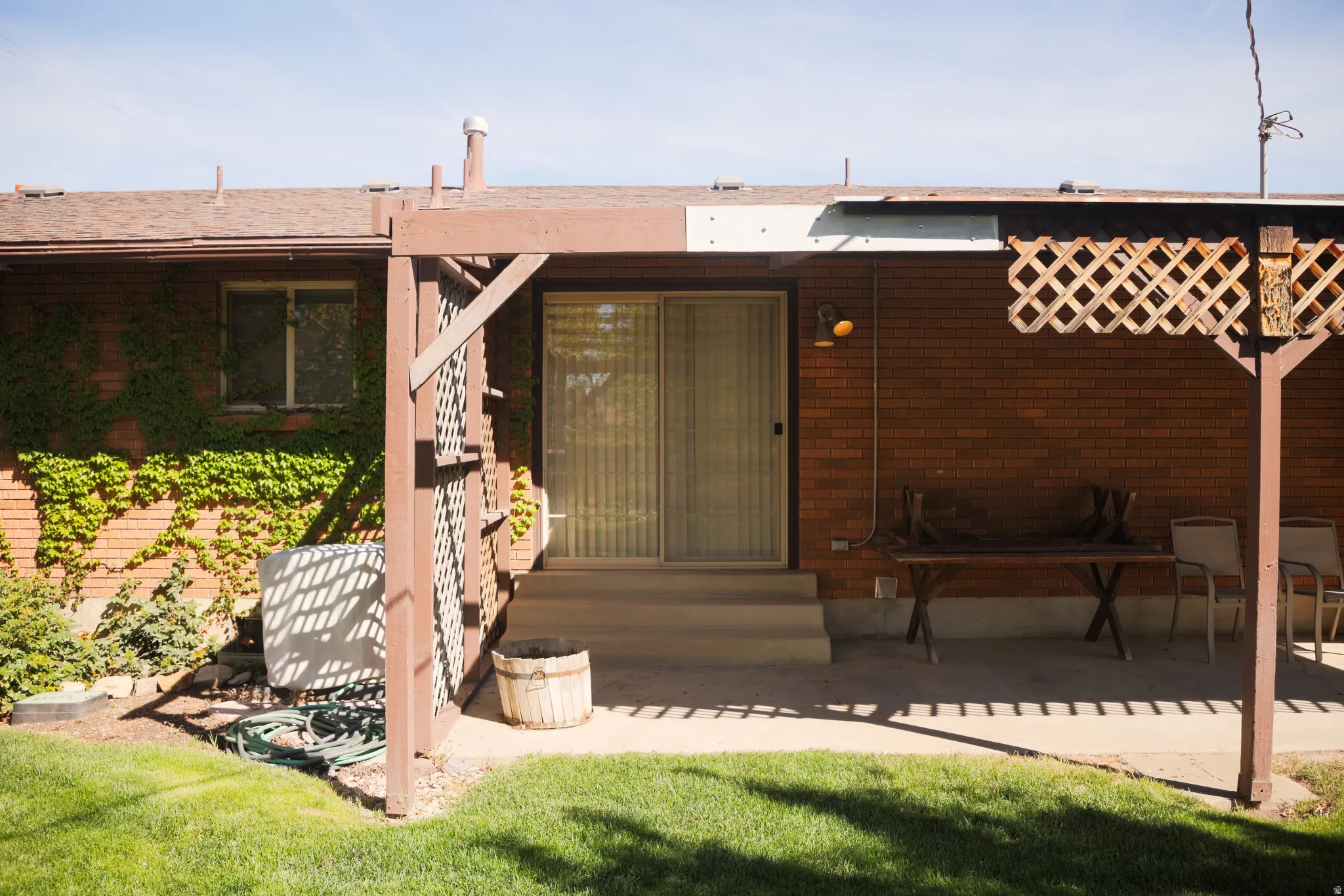 Doorway to property with brick siding, a patio area, and a lawn