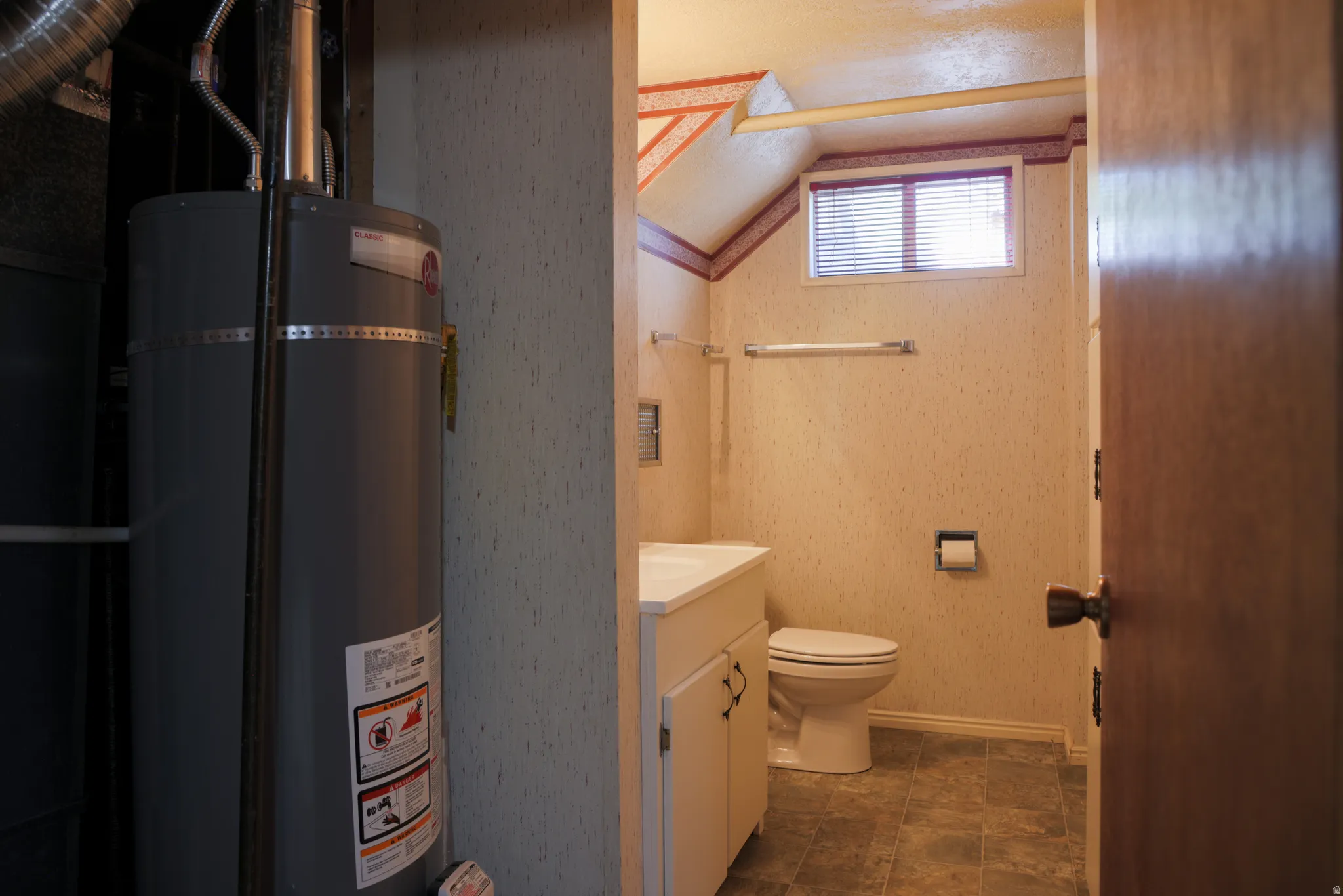 Half bath featuring strapped water heater, and vanity