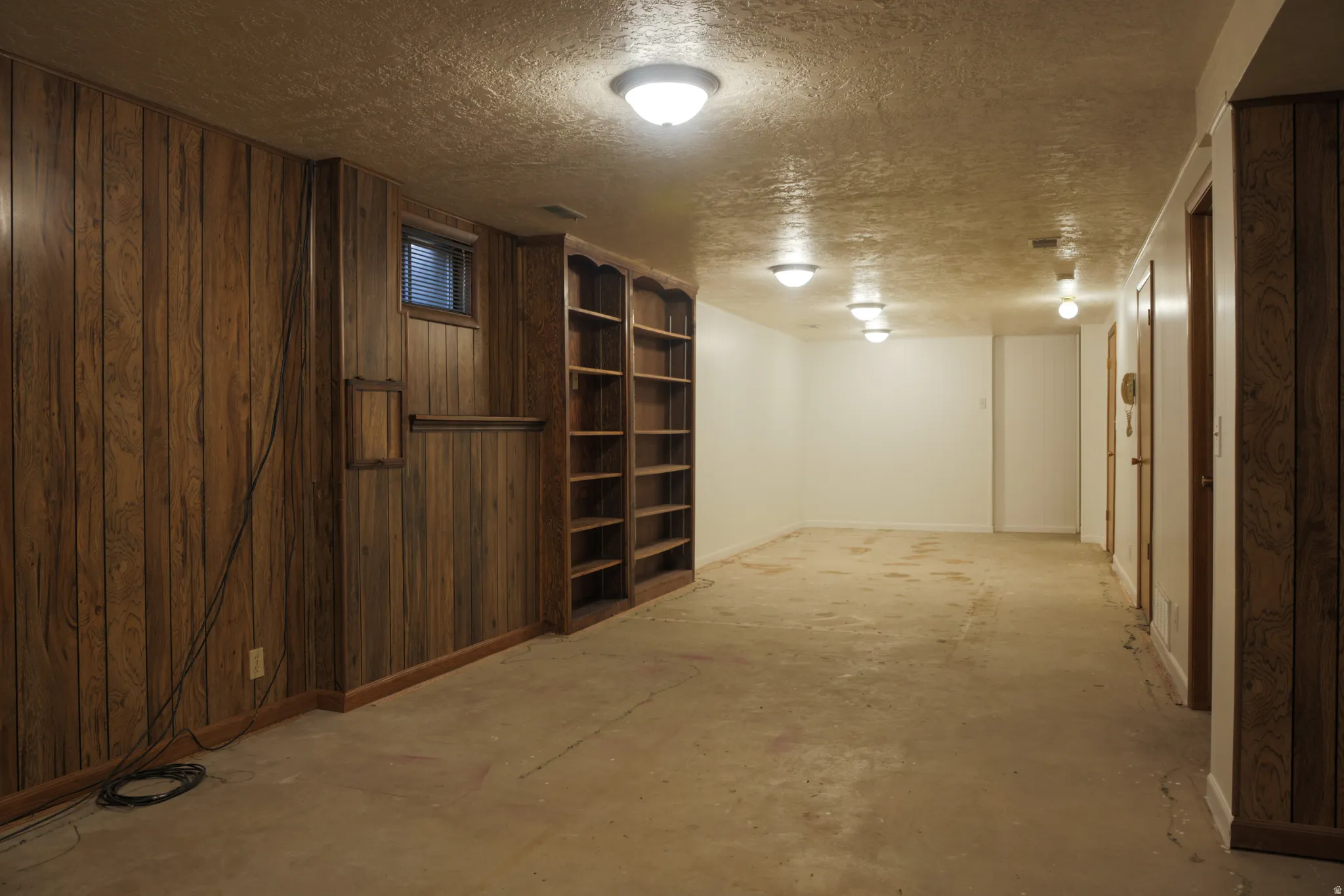 Finished basement area with a textured ceiling and baseboards