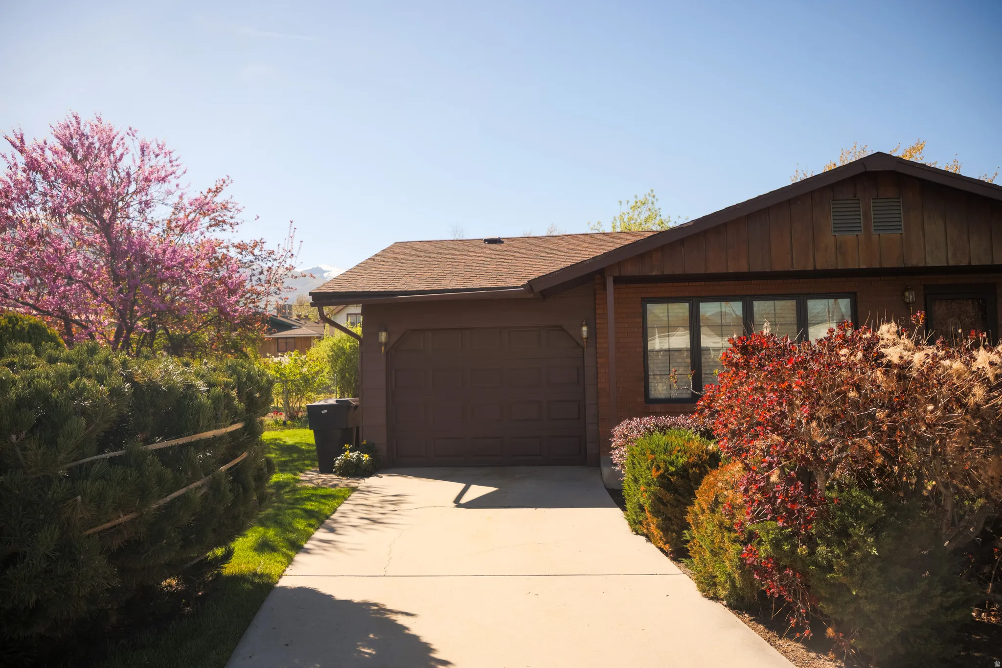 View of front of house with a garage, driveway, roof with shingles, and board and batten siding