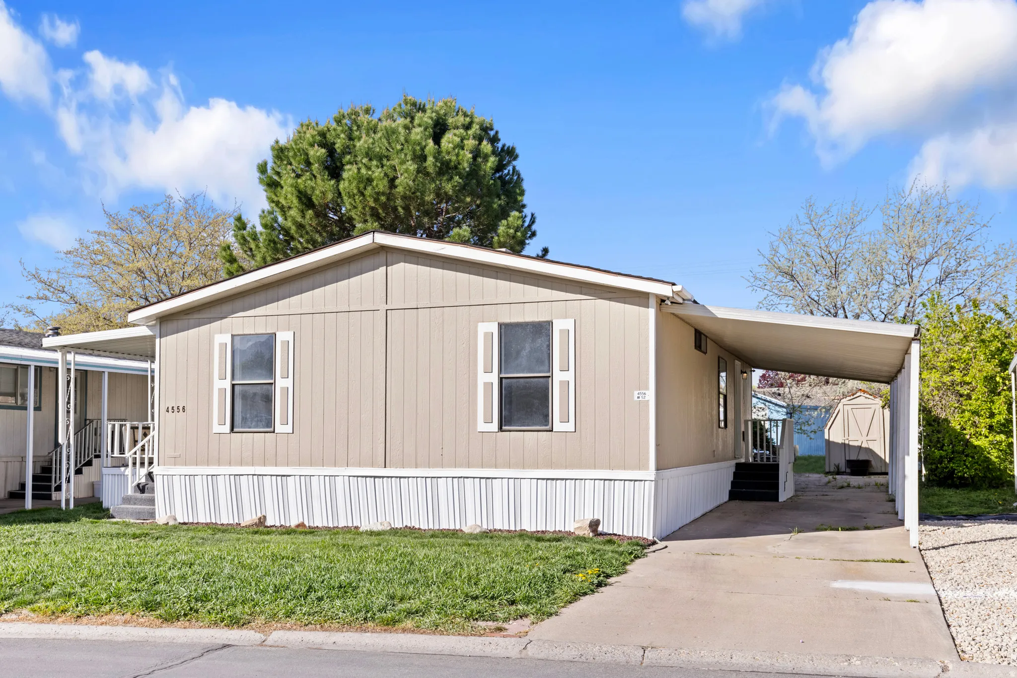 View of home's exterior featuring an attached carport, driveway, a storage shed, and a yard