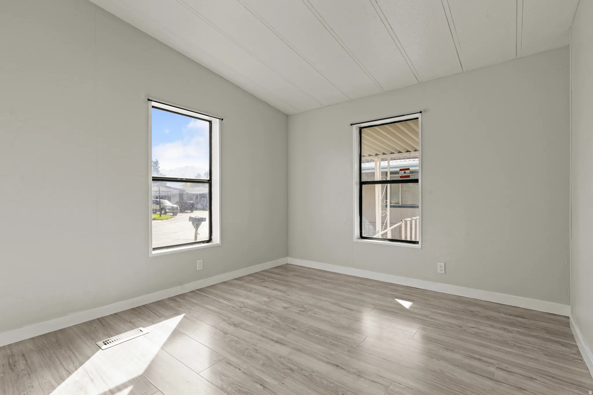 Spare room featuring light wood finished floors and lofted ceiling