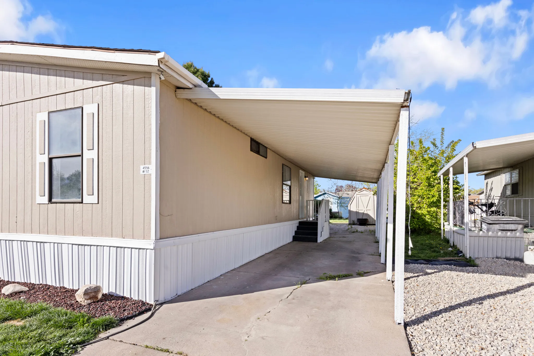 View of side of home featuring a carport, driveway, and a storage unit