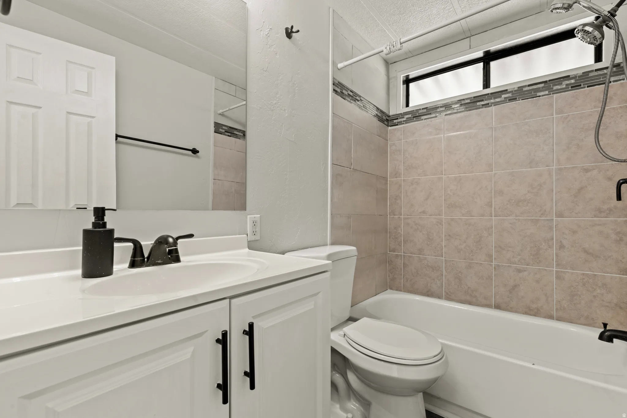 Full bath featuring vanity, shower / bathtub combination, and a textured wall