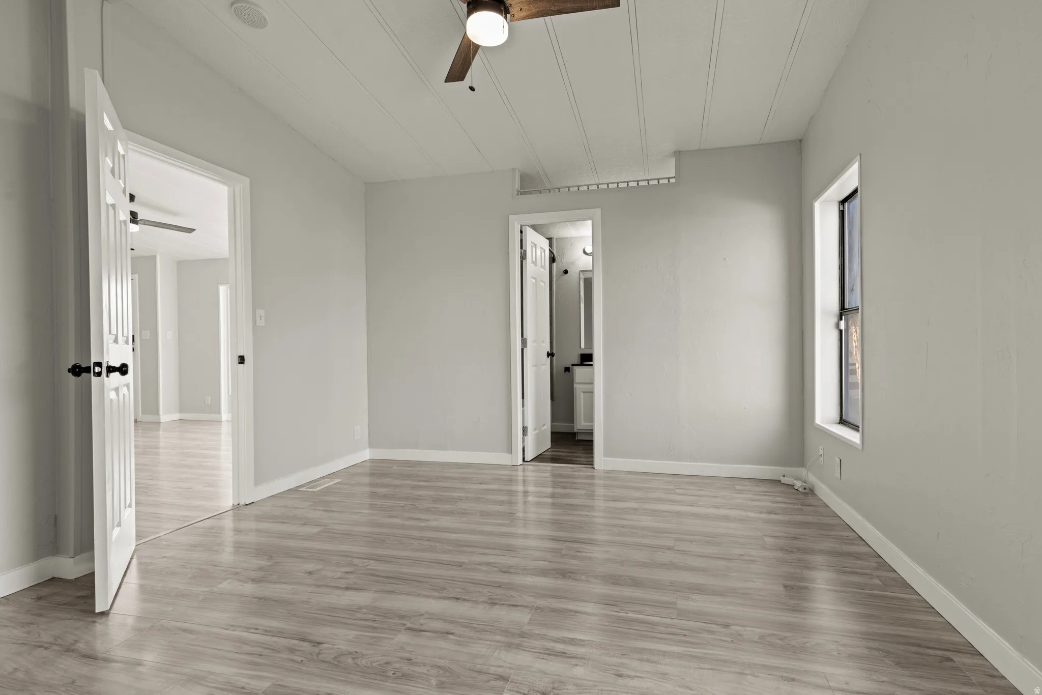 Unfurnished bedroom with light wood-style floors, a ceiling fan, and ensuite bathroom