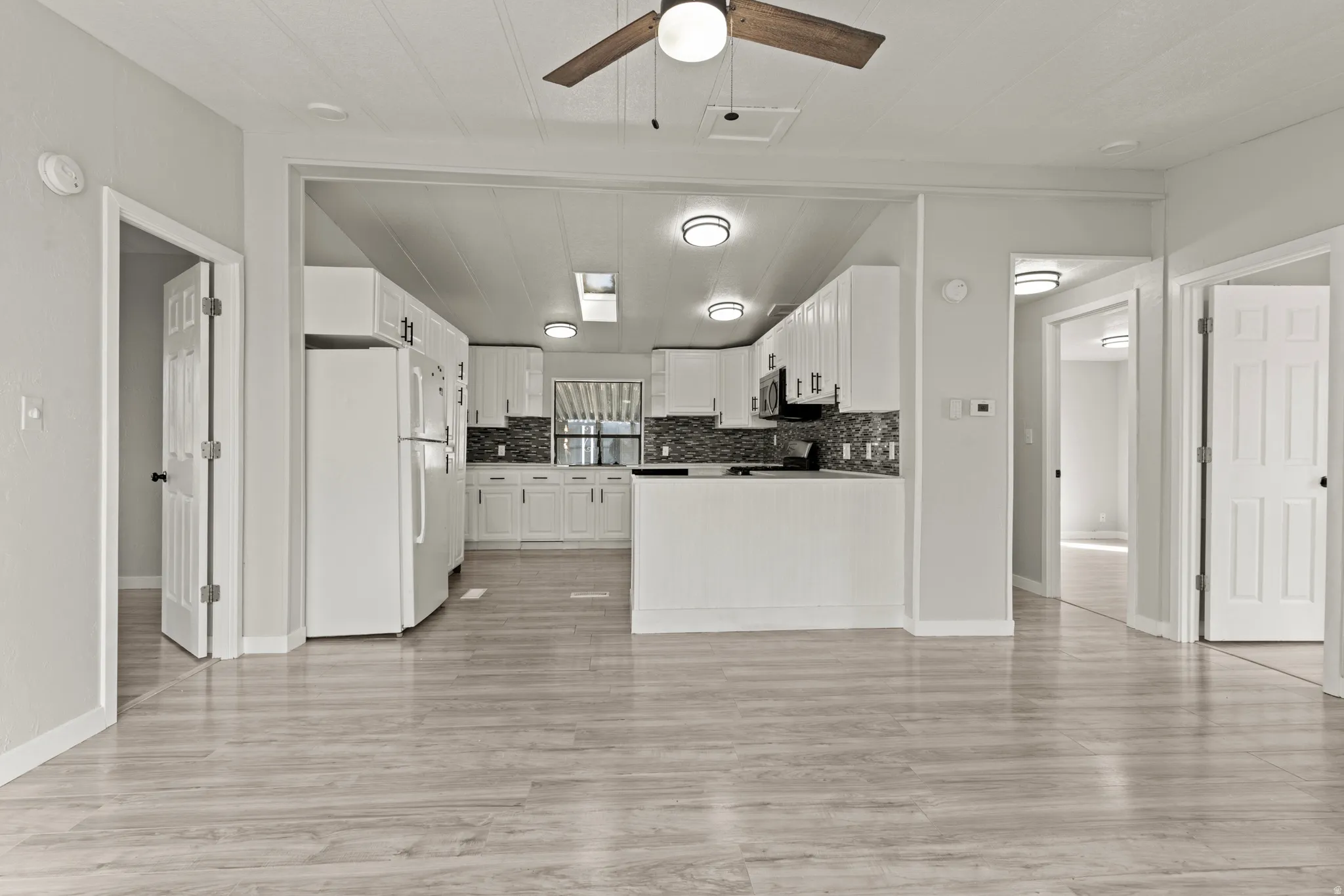 Kitchen featuring white cabinetry, ceiling fan, and freestanding refrigerator