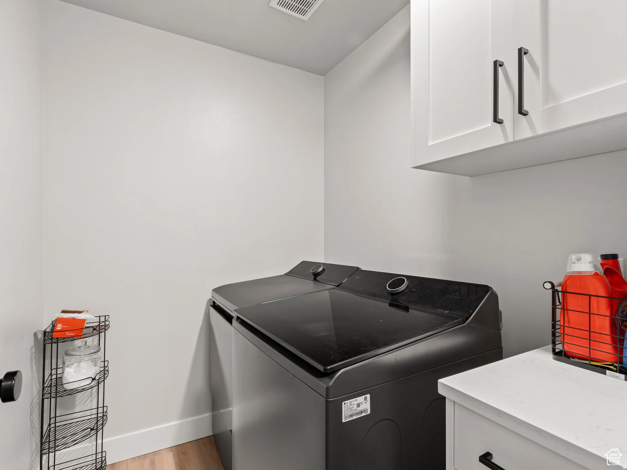 Laundry room featuring washer / clothes dryer, cabinet space, and light wood-style flooring