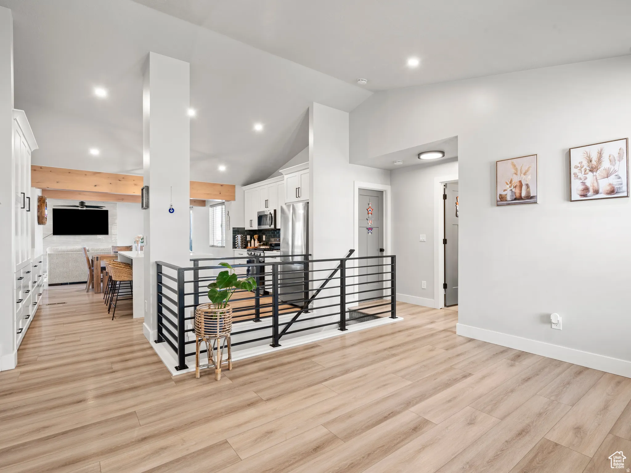 Hall with an upstairs landing, vaulted ceiling, light wood-style floors, and recessed lighting