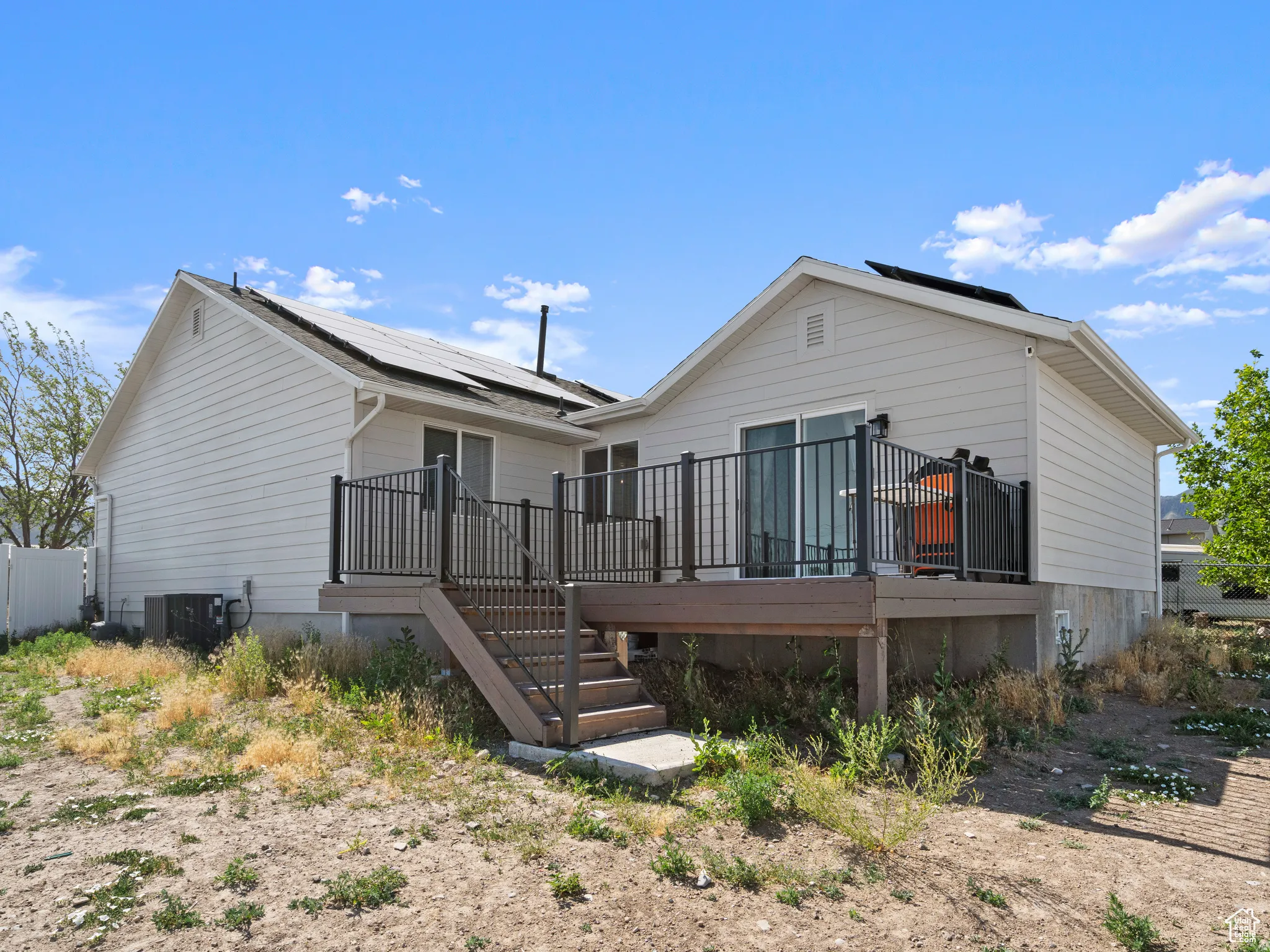 Rear view of property featuring roof mounted solar panels and a deck