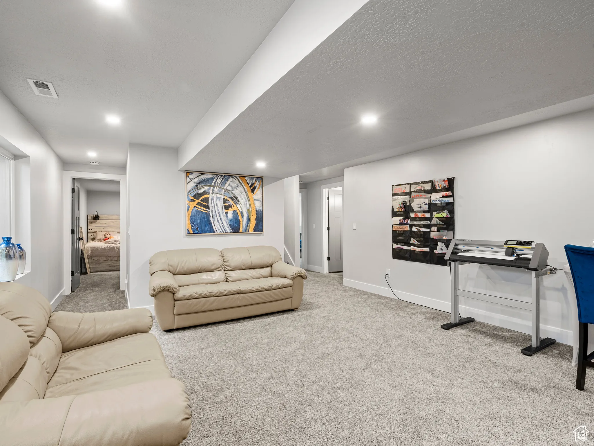 Finished basement living area with light colored carpet, recessed canned lighting, and a textured ceilin.