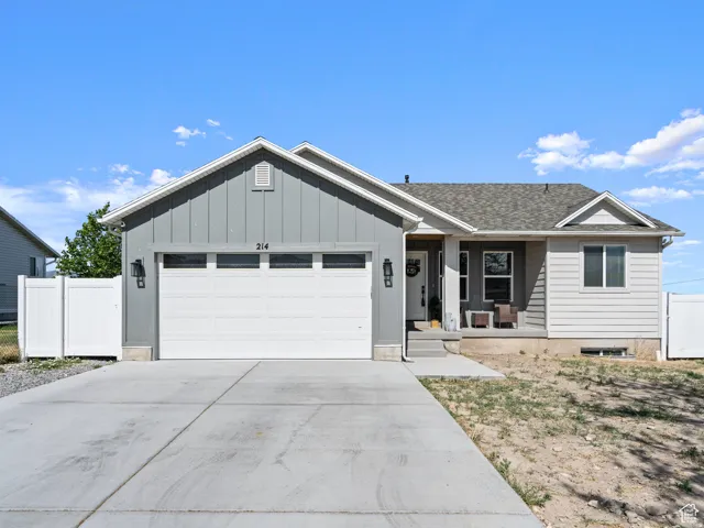 Rambler home, featuring a garage, driveway, a shingled roof, and board and batten siding