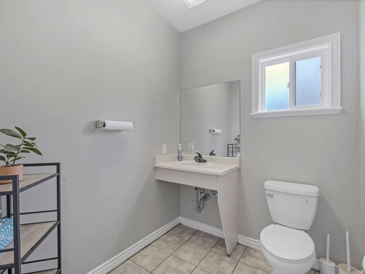 Bathroom featuring toilet, sink and light tile patterned flooring