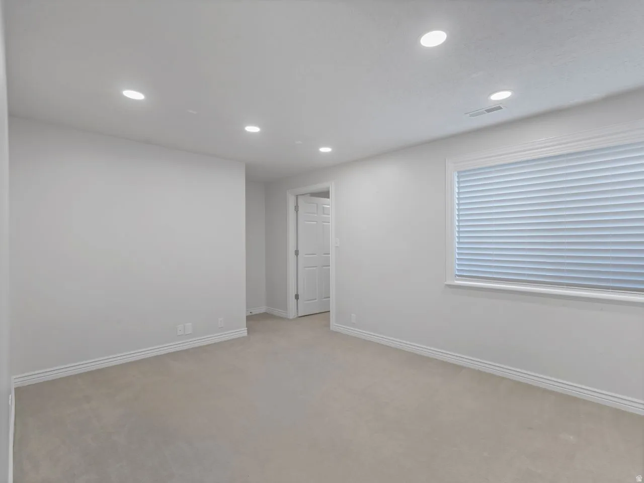 Empty room with recessed lighting and light carpet