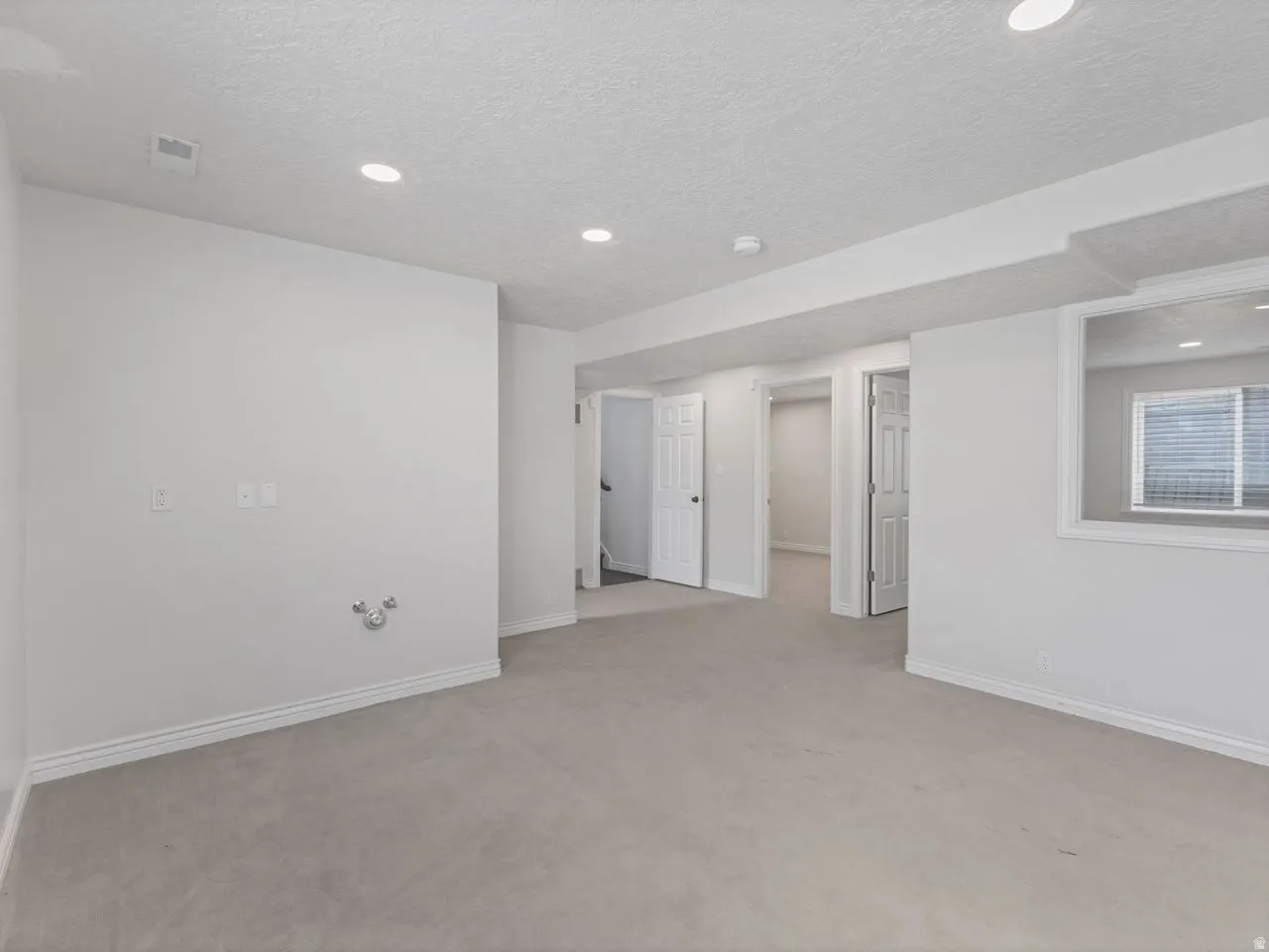 Open area featuring light colored carpet, a textured ceiling, and recessed lighting