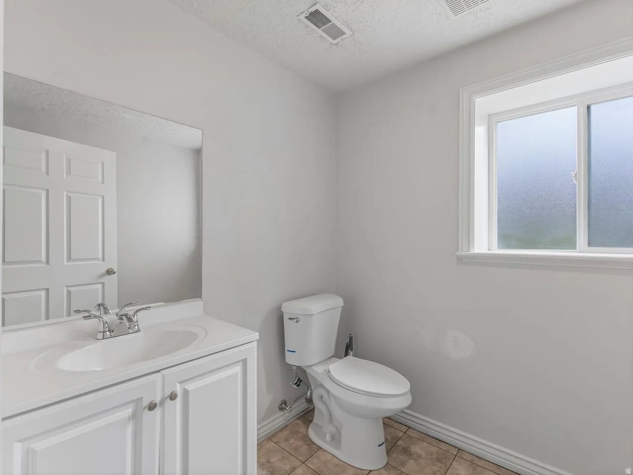 Bathroom featuring vanity, a textured ceiling, and light tile patterned floors