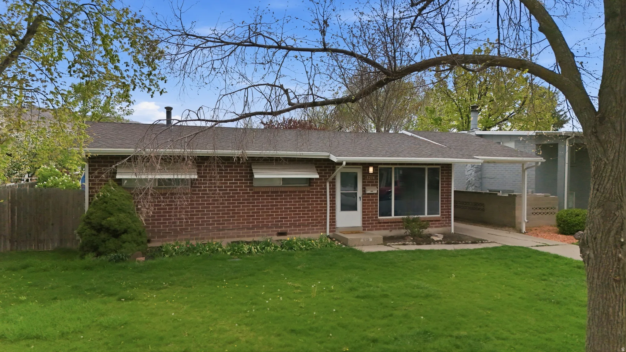 View of front facade featuring brick siding, roof with shingles, and crawl space