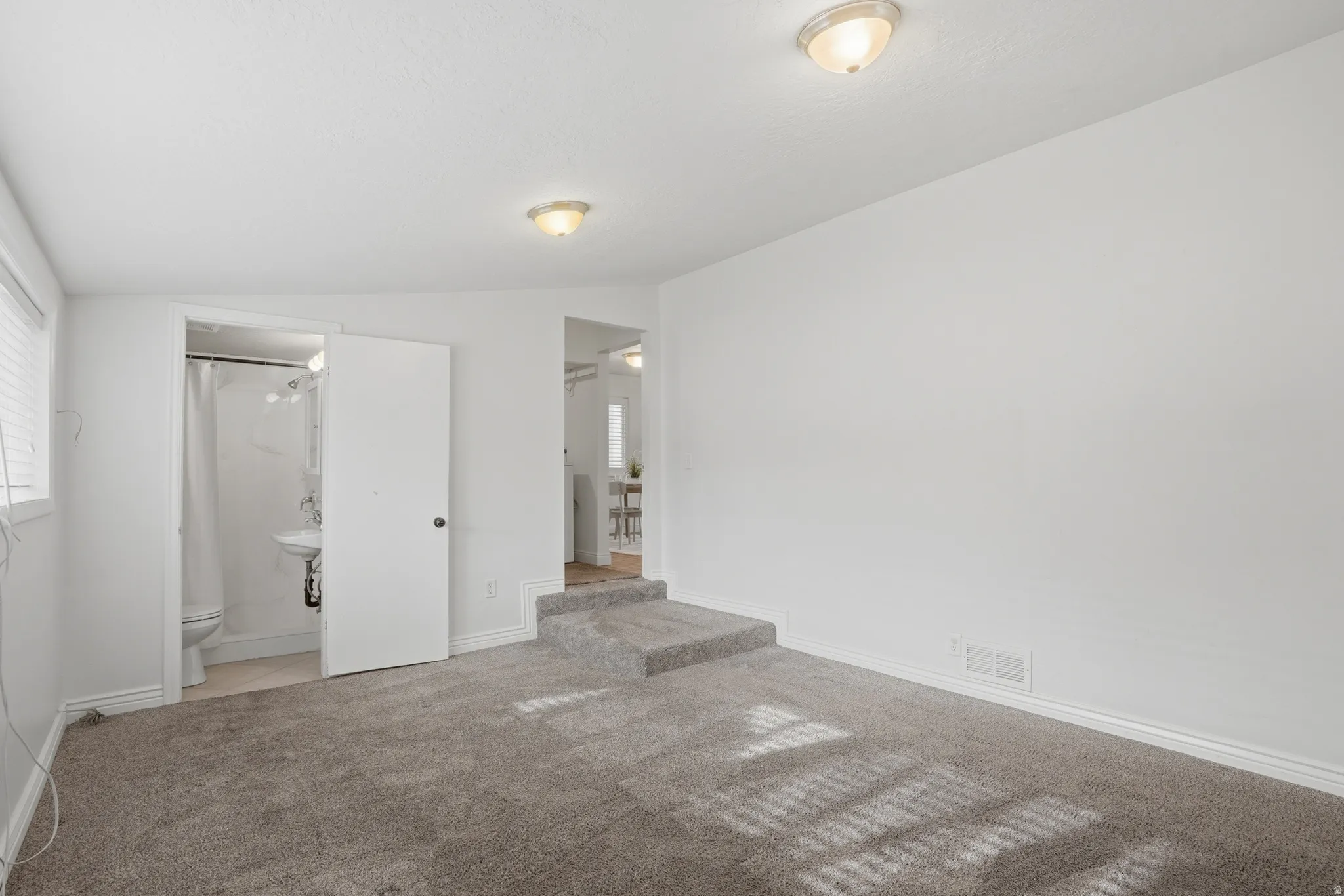 Family room with lofted ceiling, light colored carpet, and ensuite bathroom