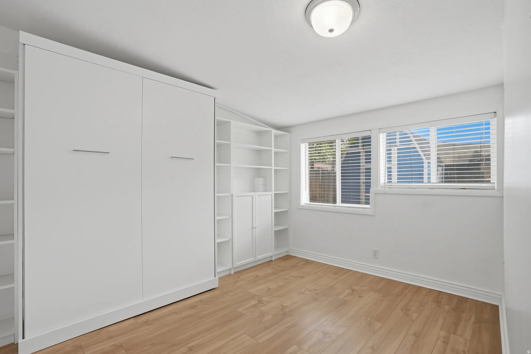 Bedroom 4 with lofted ceiling, light wood-style floors, and a closet