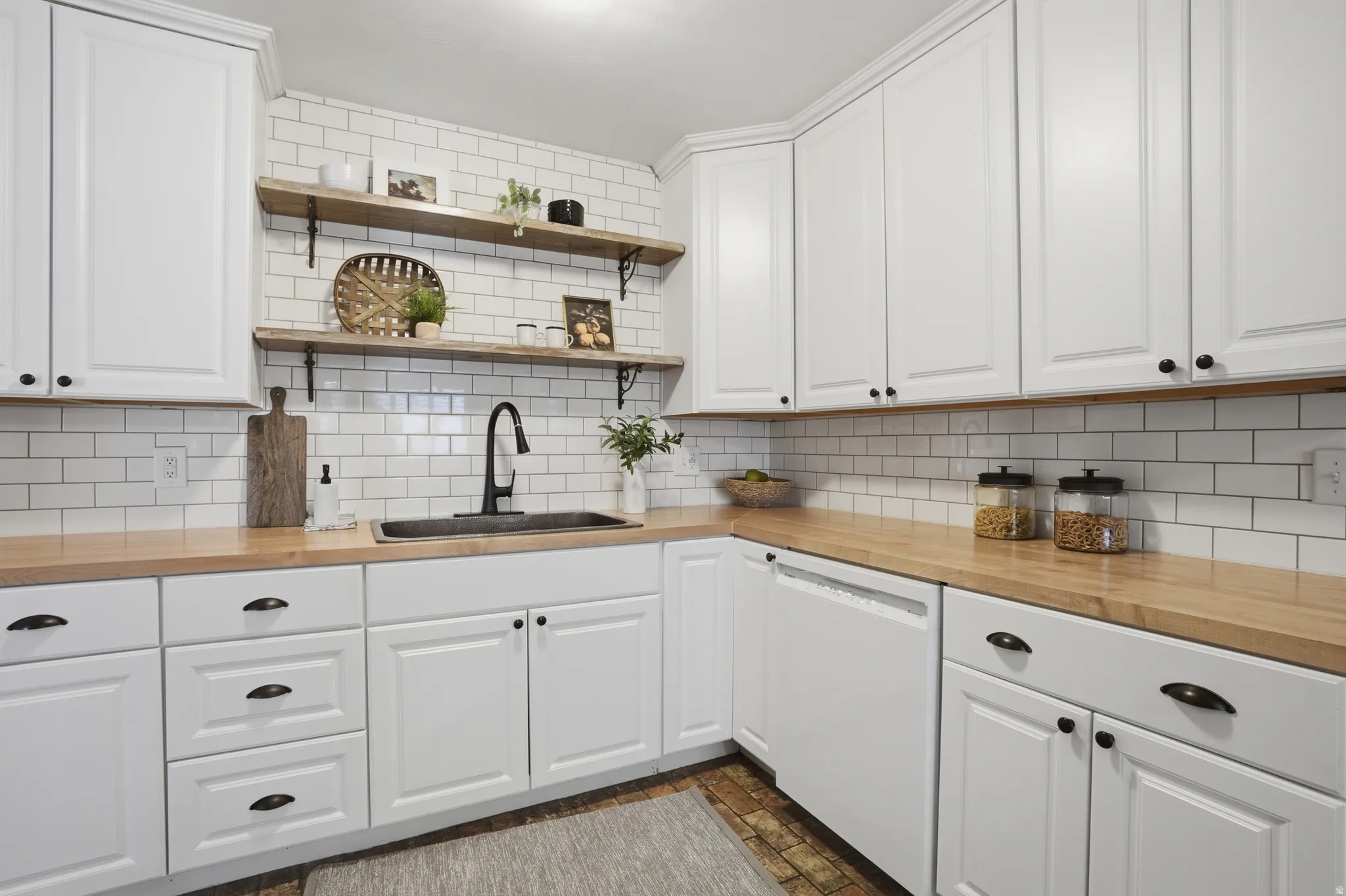Kitchen with wood counters, white cabinets, and dishwasher