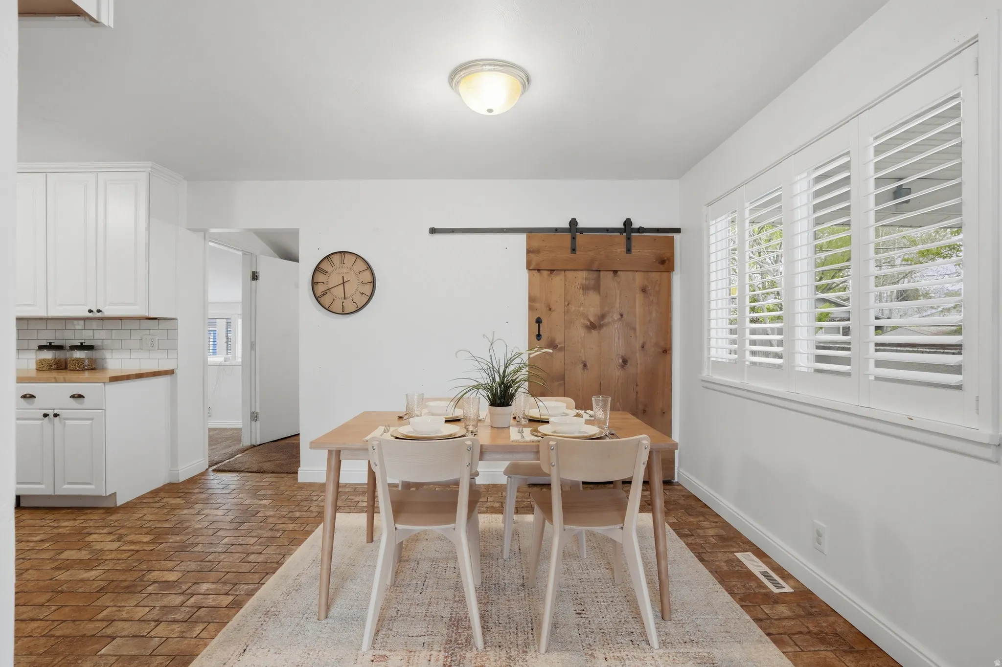 Dining area with a barn door and brick floors