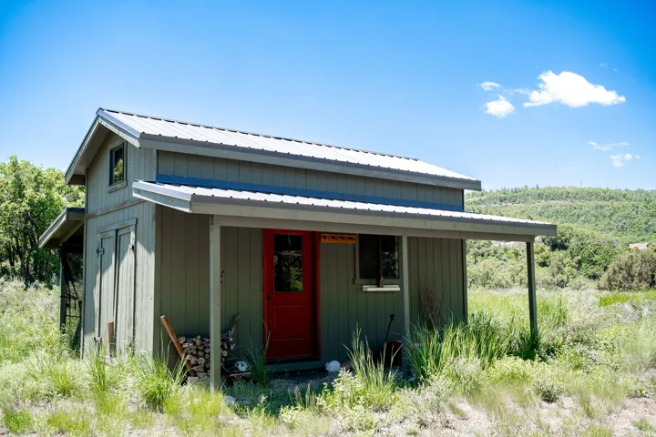 Green wood-paneled exterior with a bright red entry door