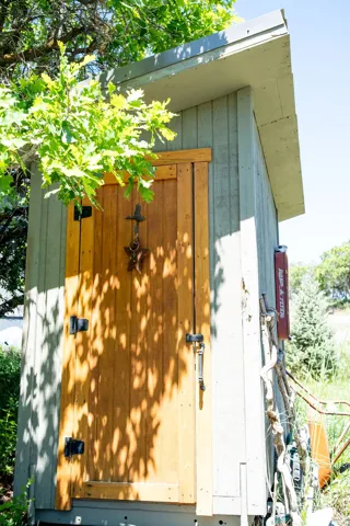 Outdoor storage structure with a natural wood door, board and batten siding, and a sloped roof