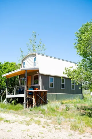 Gambrel roofline with an upper-level dormer, covered front porch, and elevated foundation