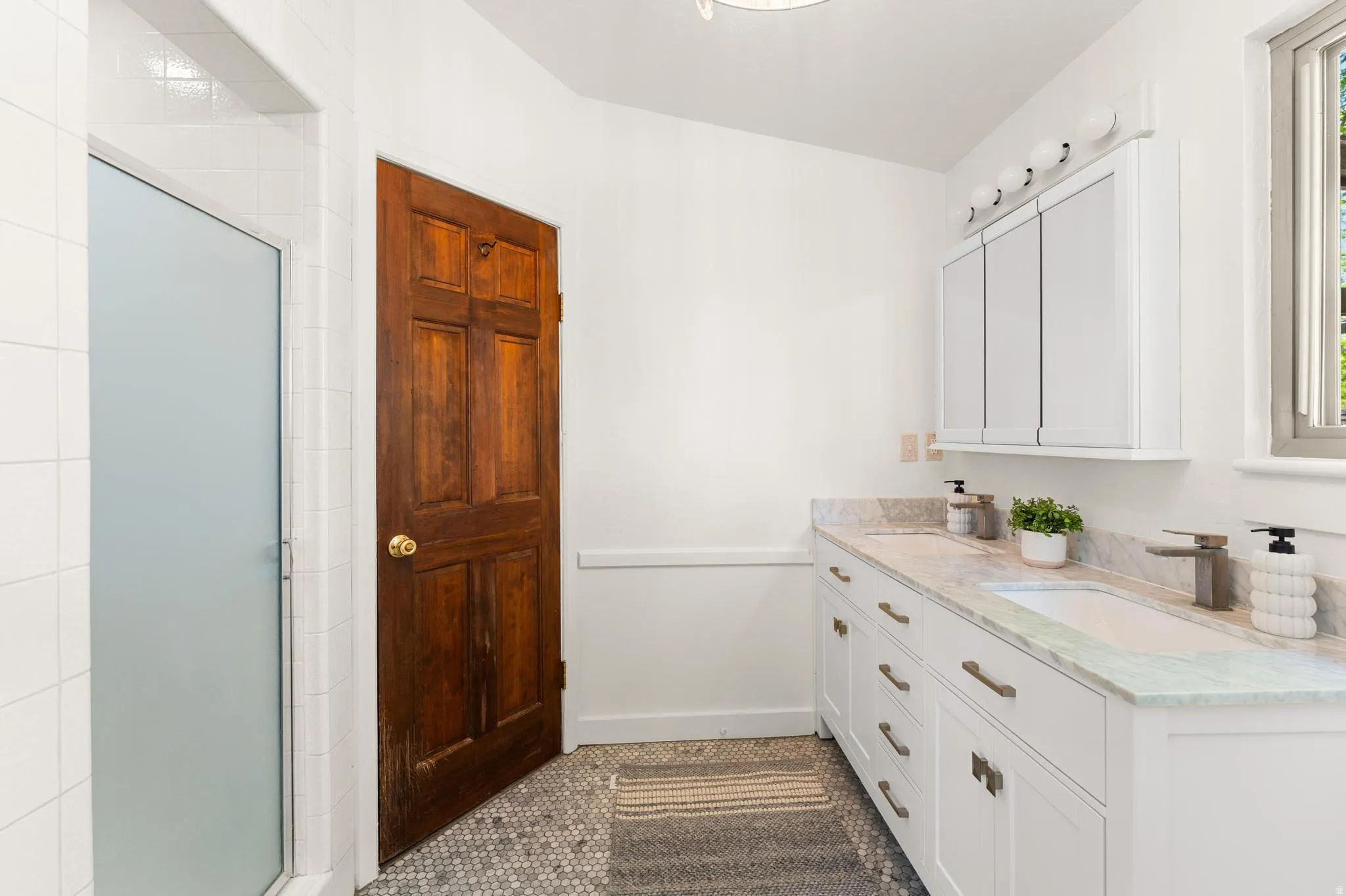 Bathroom with double vanity, a stall shower, plenty of natural light, and dark tile patterned floors