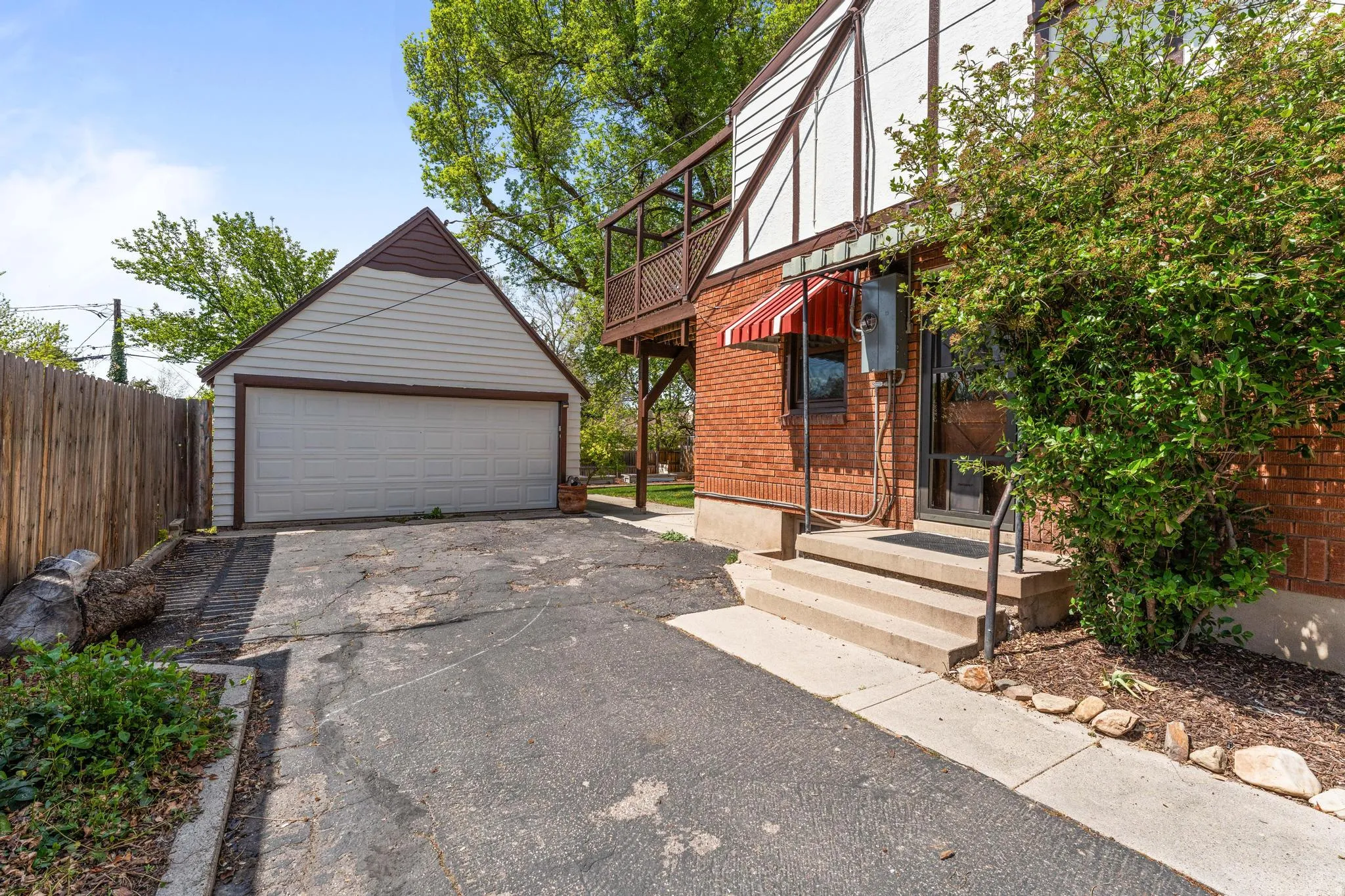 View of front of property with an outdoor structure, a detached garage, brick siding, and a balcony