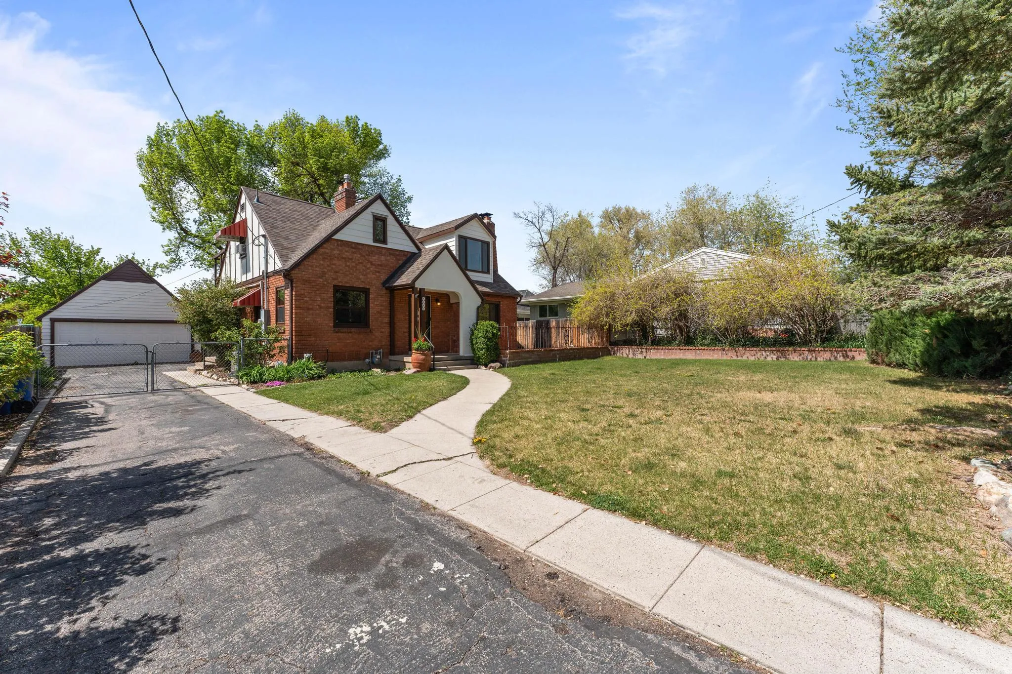Tudor house with an outbuilding, brick siding, a chimney, and a detached garage