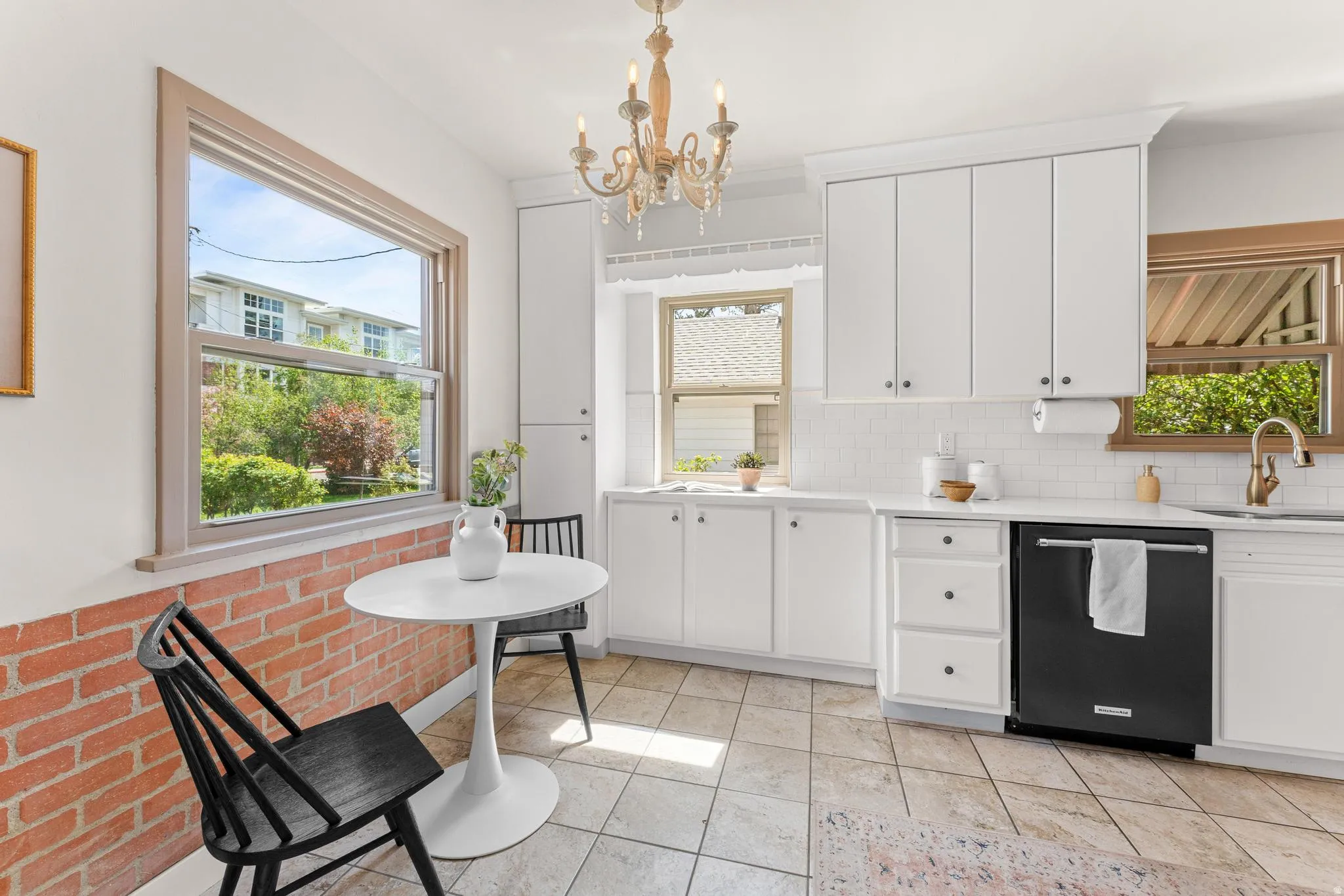 Kitchen featuring white cabinets, dishwasher, suspended lighting, decorative backsplash, and light tile patterned floors