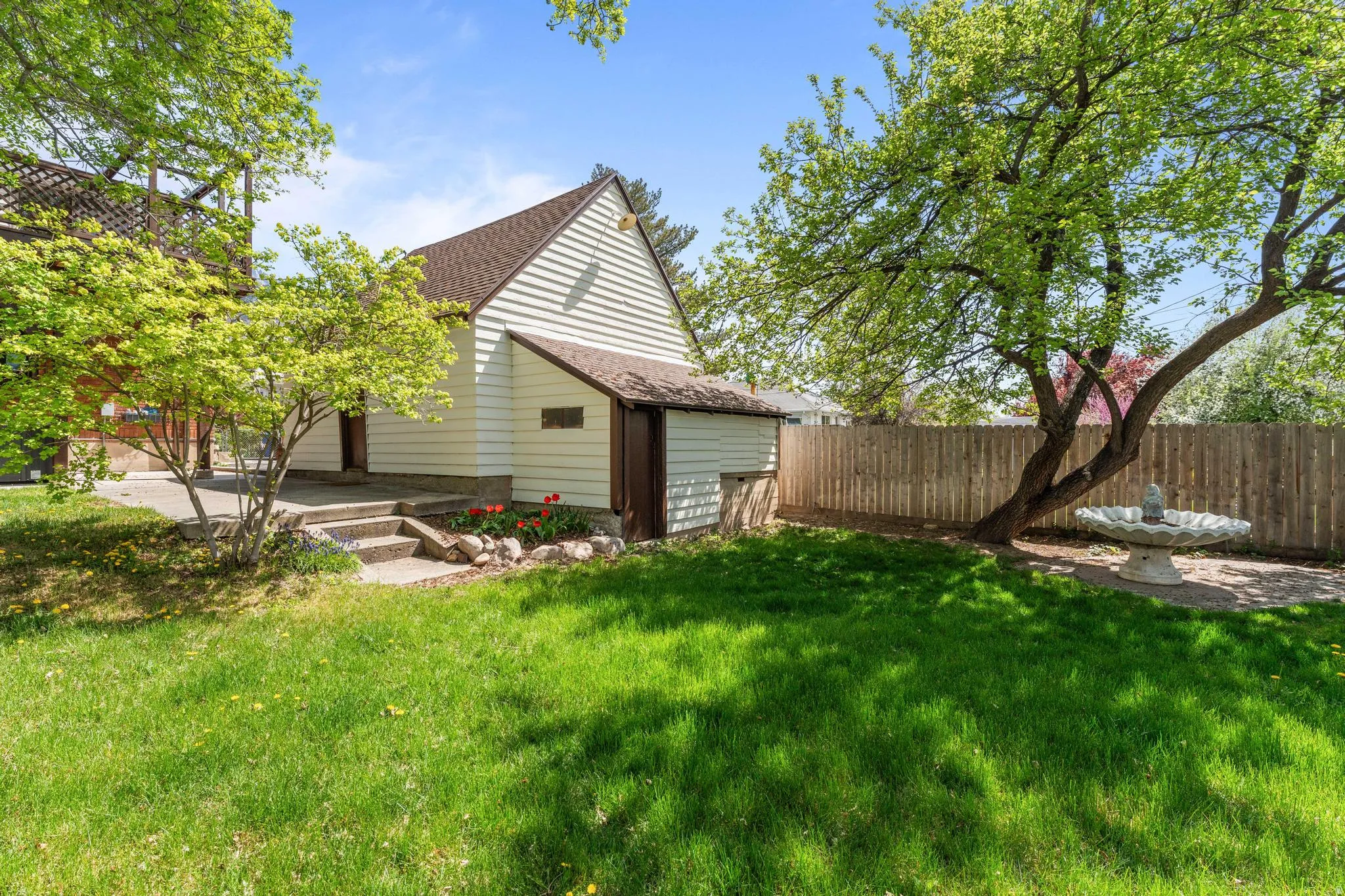 Rear view of property with a shingled roof, a fenced backyard, and a patio area